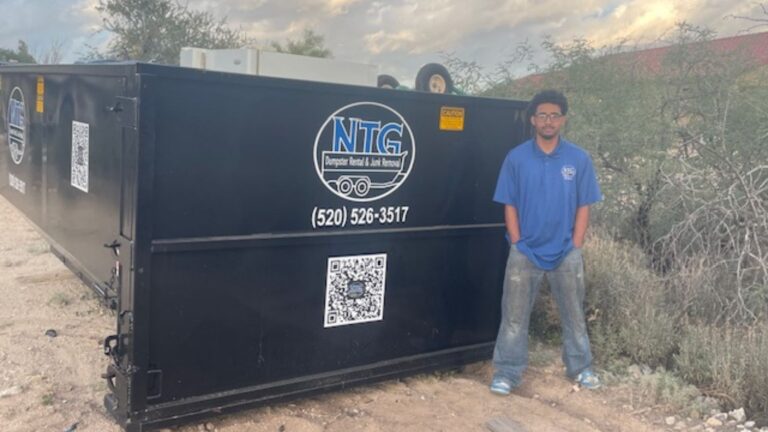 NTG Waste Removal standing at the rear of a 20 yard roll-off dumpster